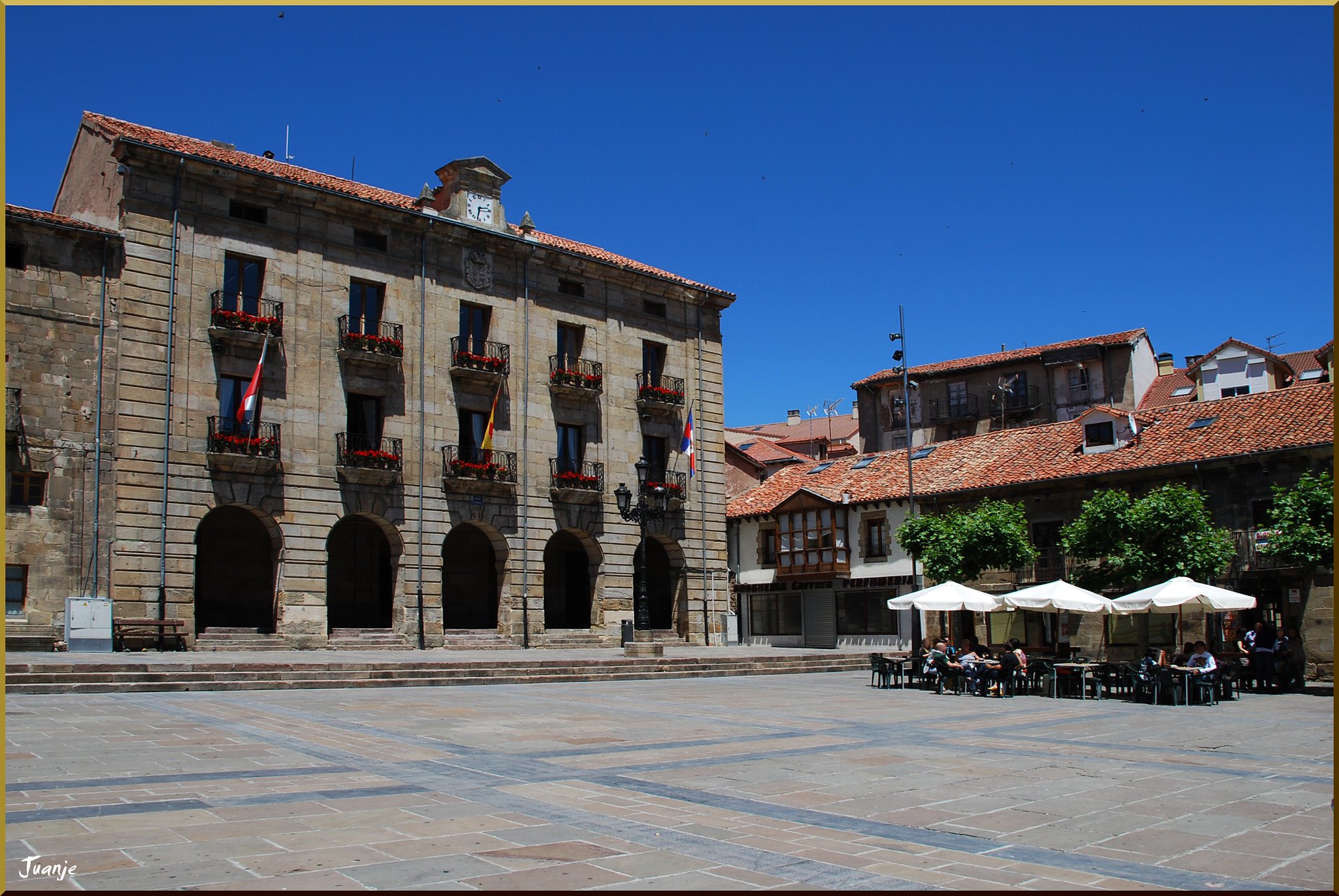 Plaza porticada con edificio de piedra y terrazas en Reinosa, Cantabria